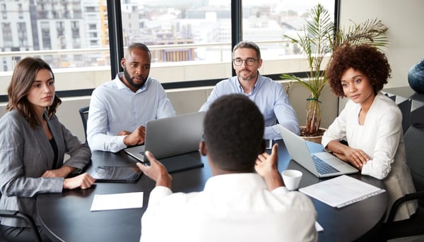 group of employees around a table talking seriously