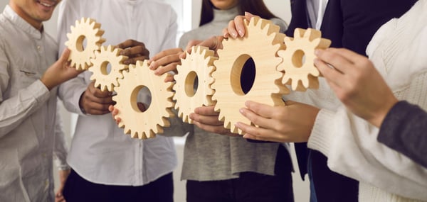 employees holding a linked chain of gears